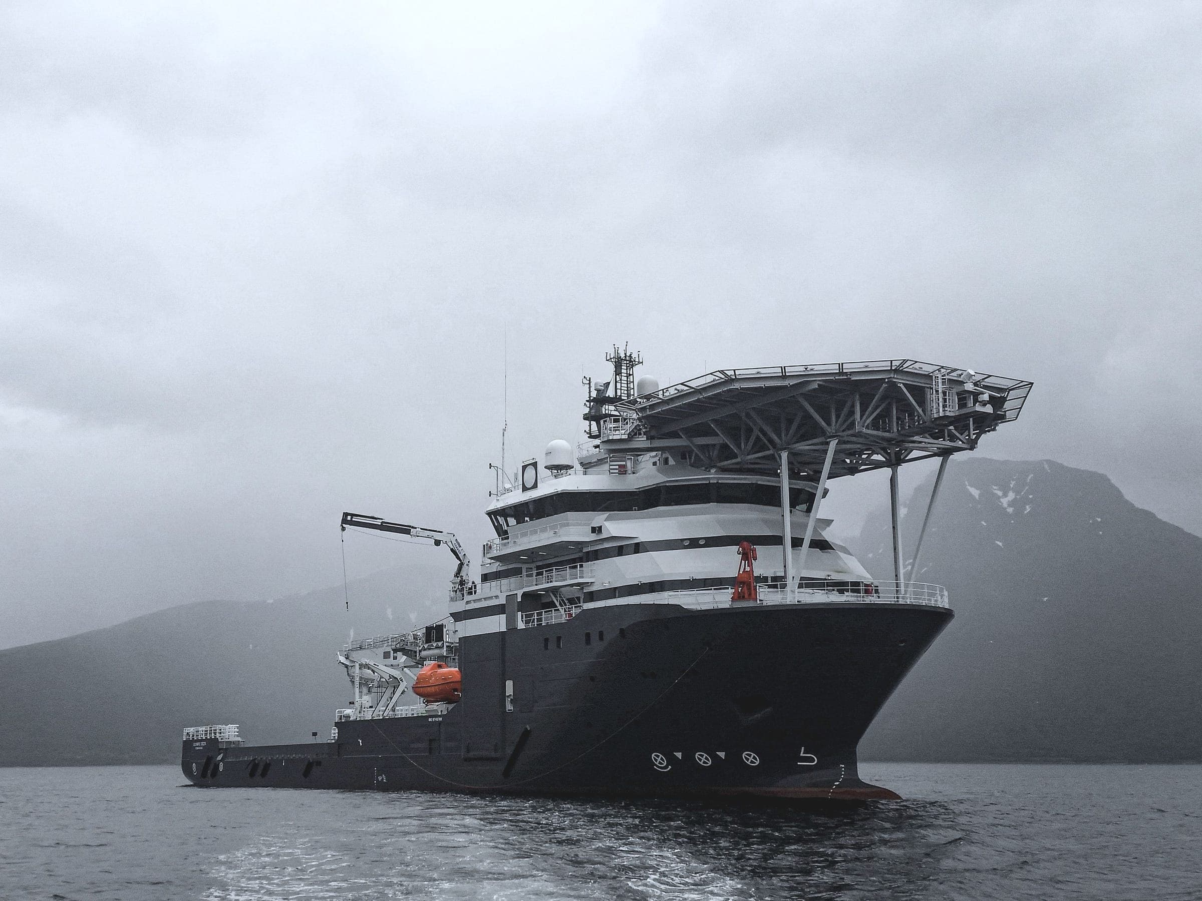 Offshorefartøy i en fjord med snødekte fjell bak